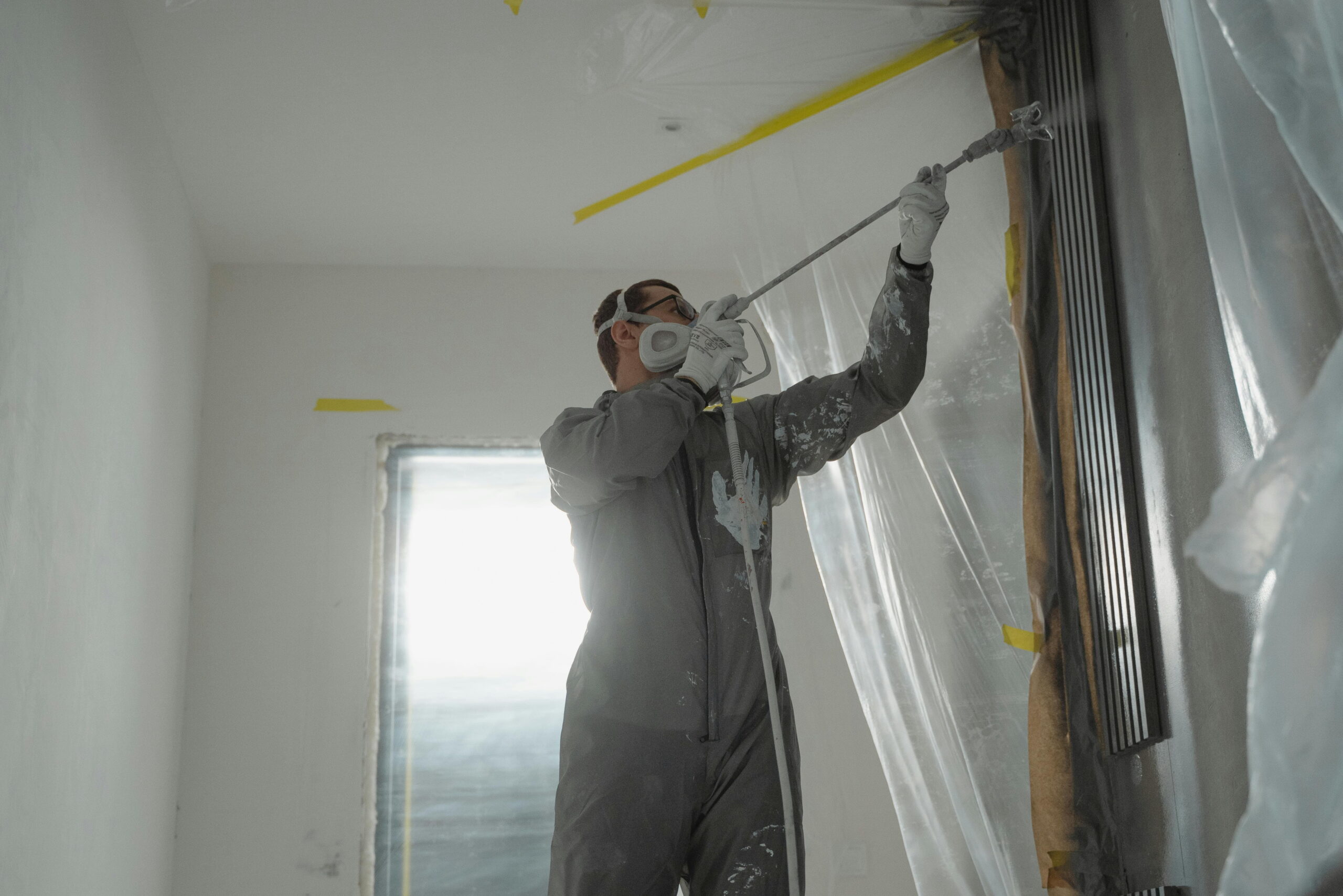 Worker spraying external render material on a wall, suitable for low-threshold door options for insulation