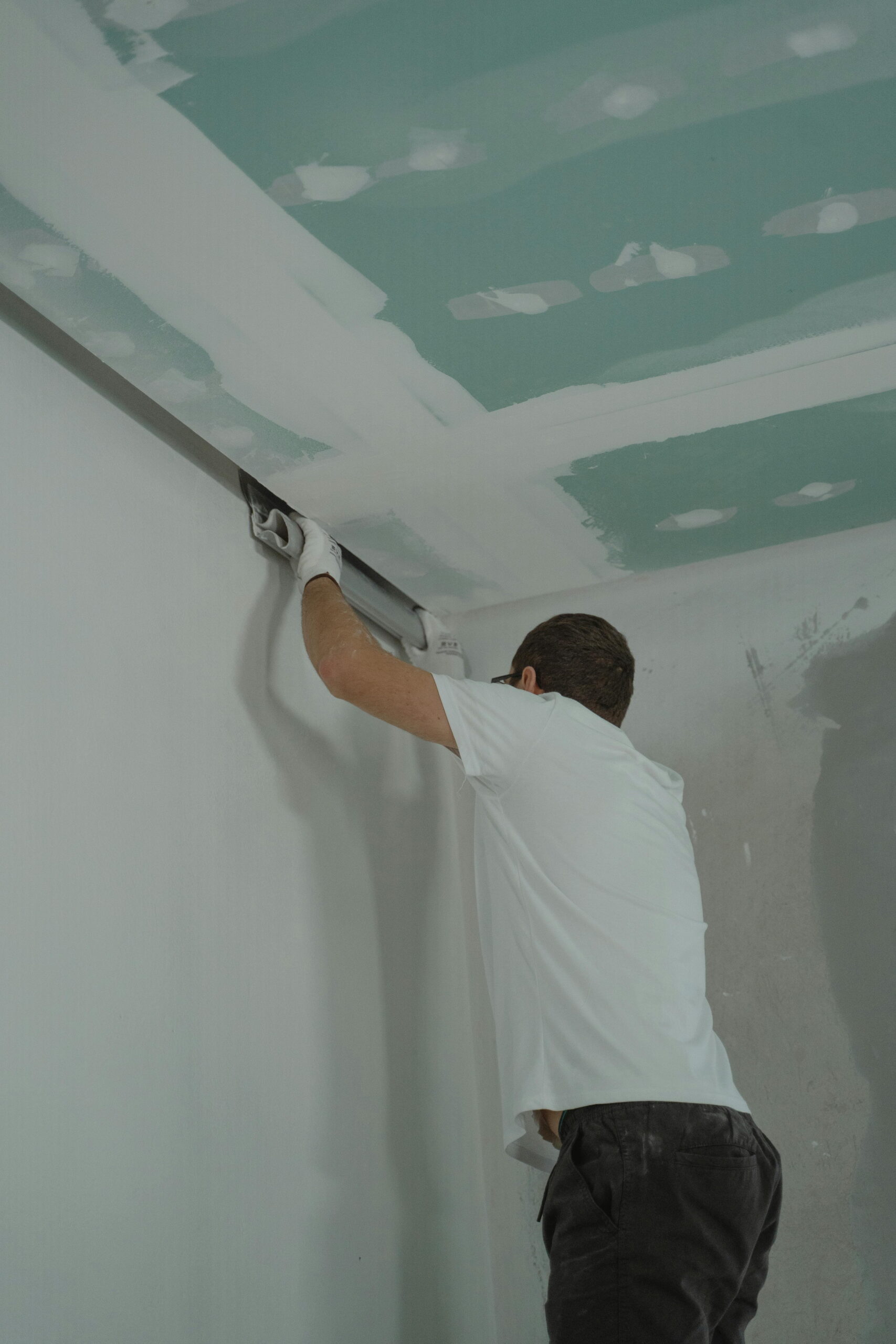 Scaffolding requirements for bungalow render showing a plasterer applying render on an internal ceiling corner