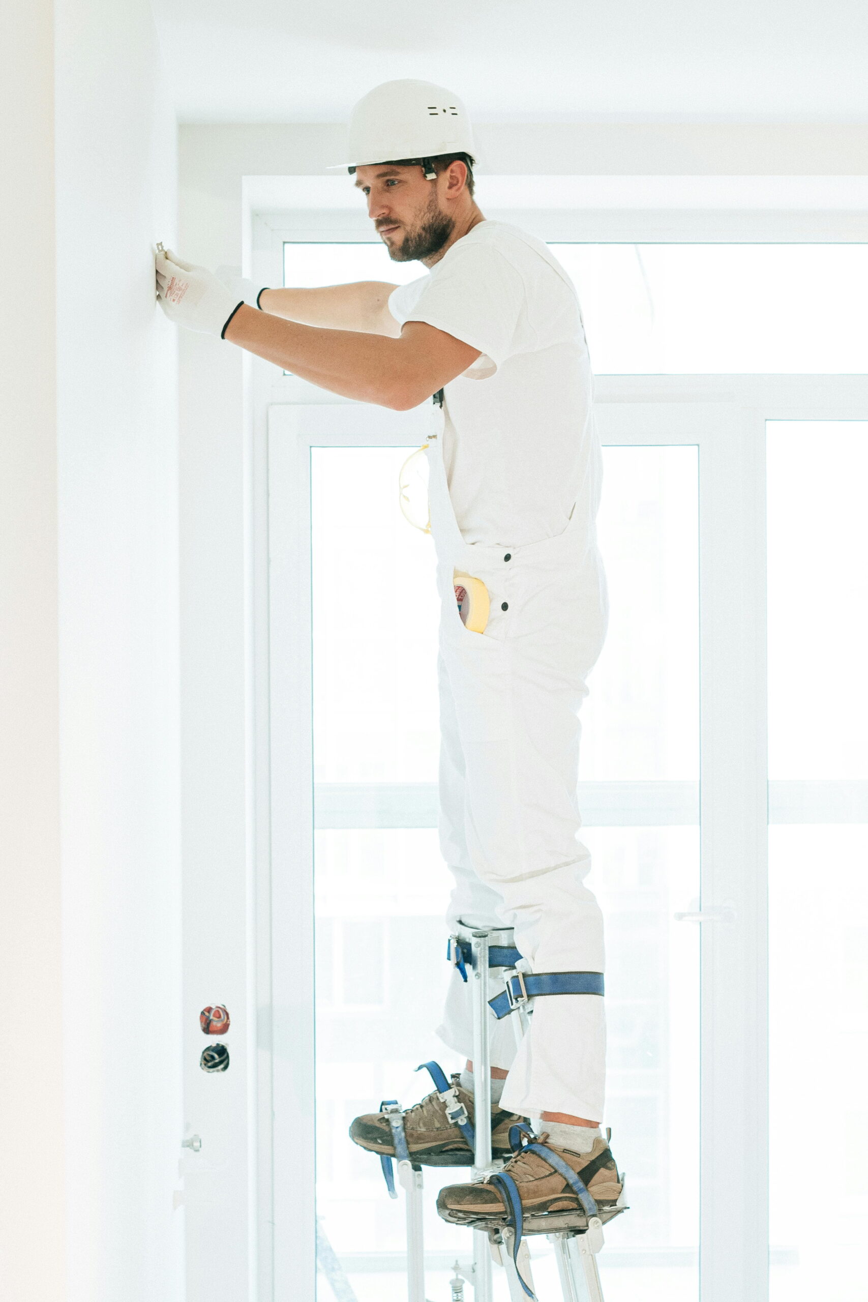 Worker demonstrating essential PPE for home rendering by using protective gear while plastering a wall