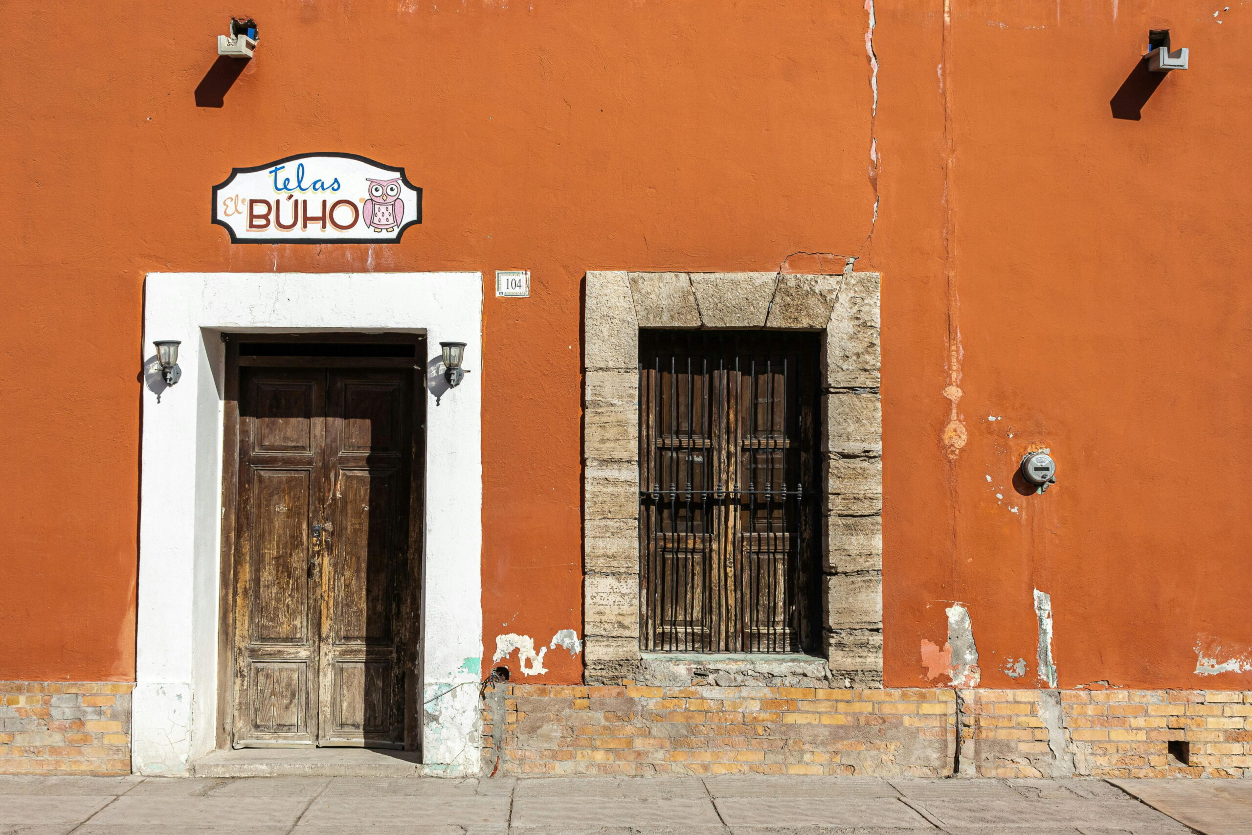 Removing algae from silicone render on an orange facade with wooden door and window