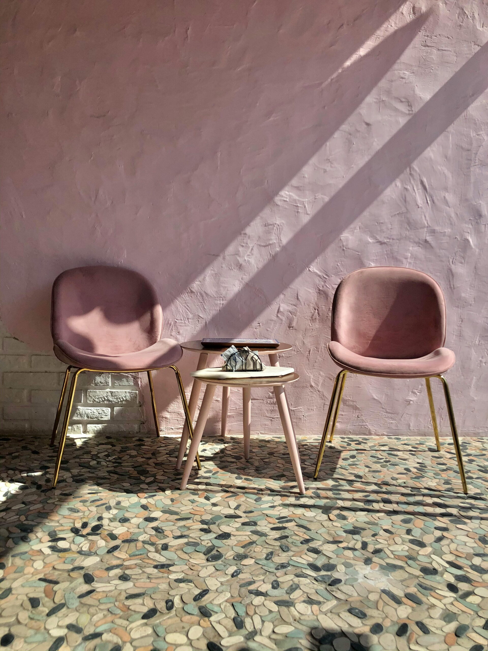 Stylish pink velvet chairs and tables with UV-resistant paint colour retention on a rendered wall