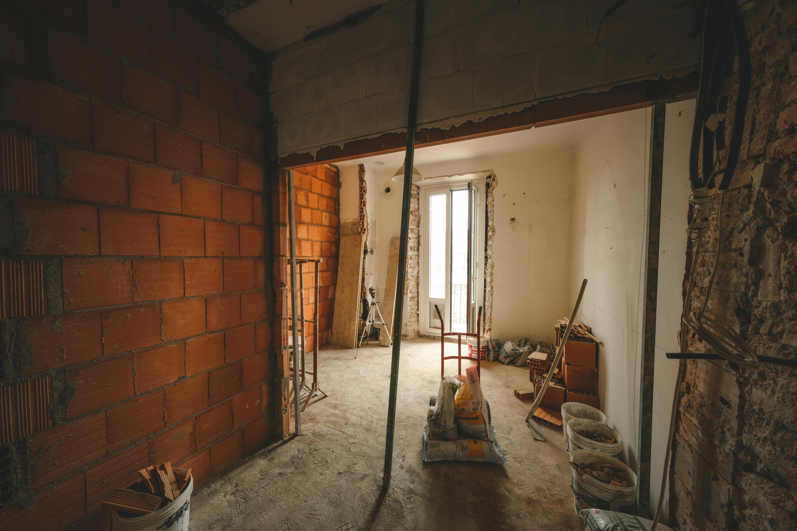 Cleaning tools after plastering at a renovation site with buckets, brushes, and scaffolding