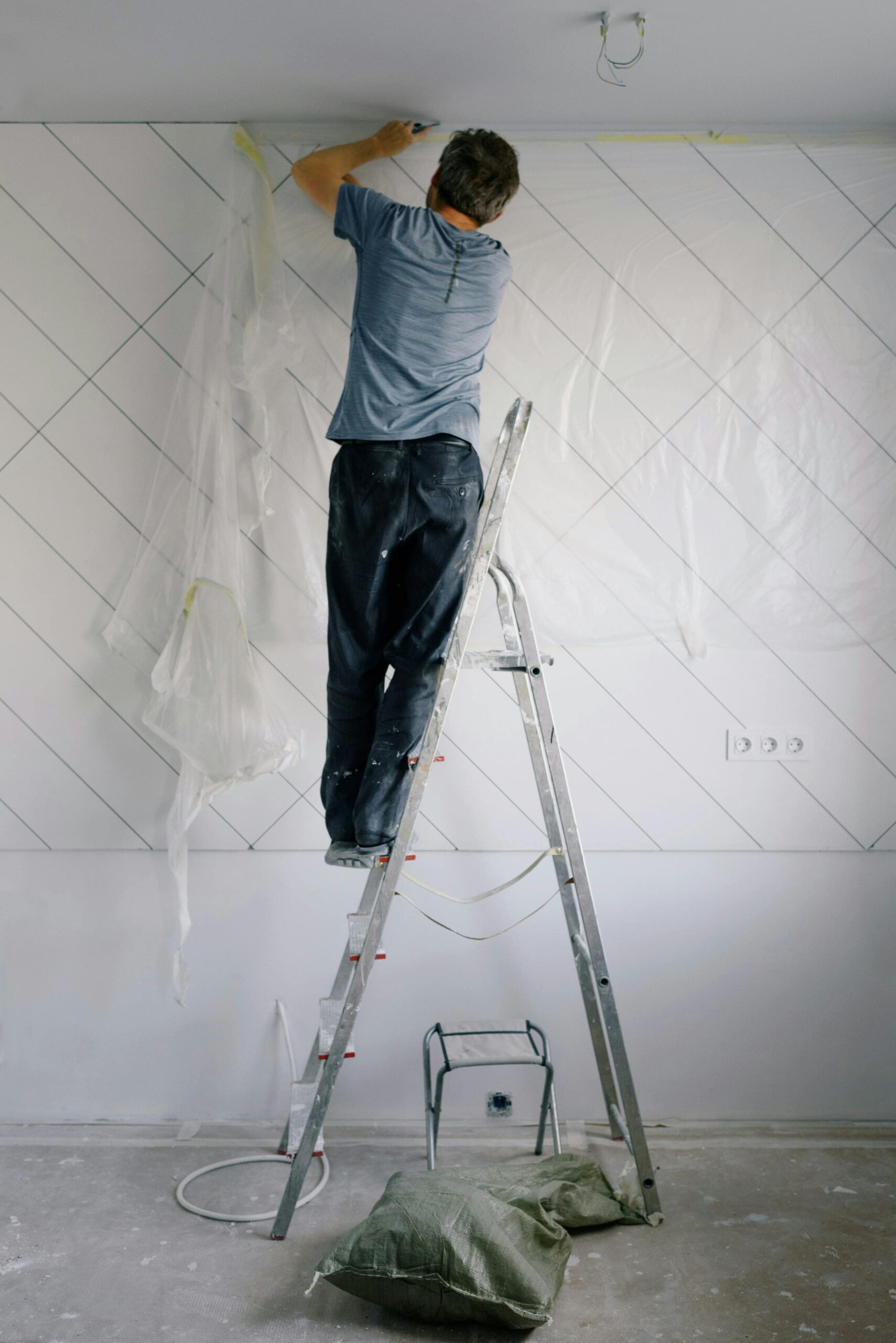 Worker troubleshooting poor adhesive bond on ceiling render