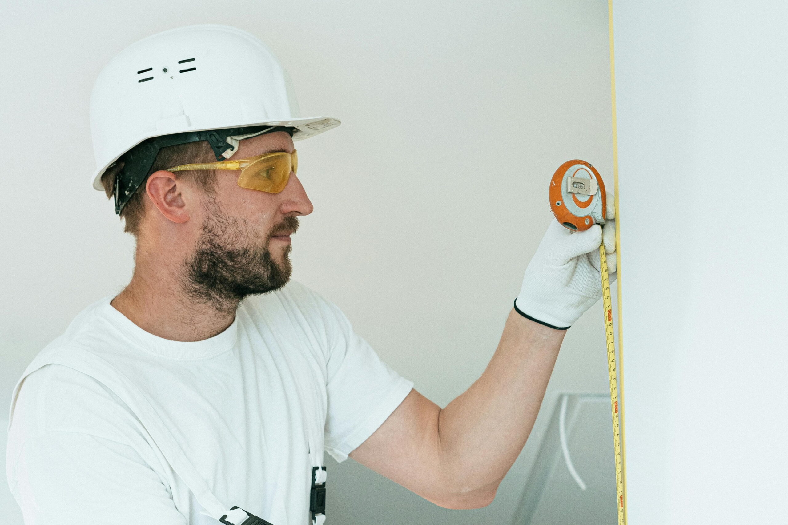 Construction worker using tape measure preparing best external wall insulation for UK climate
