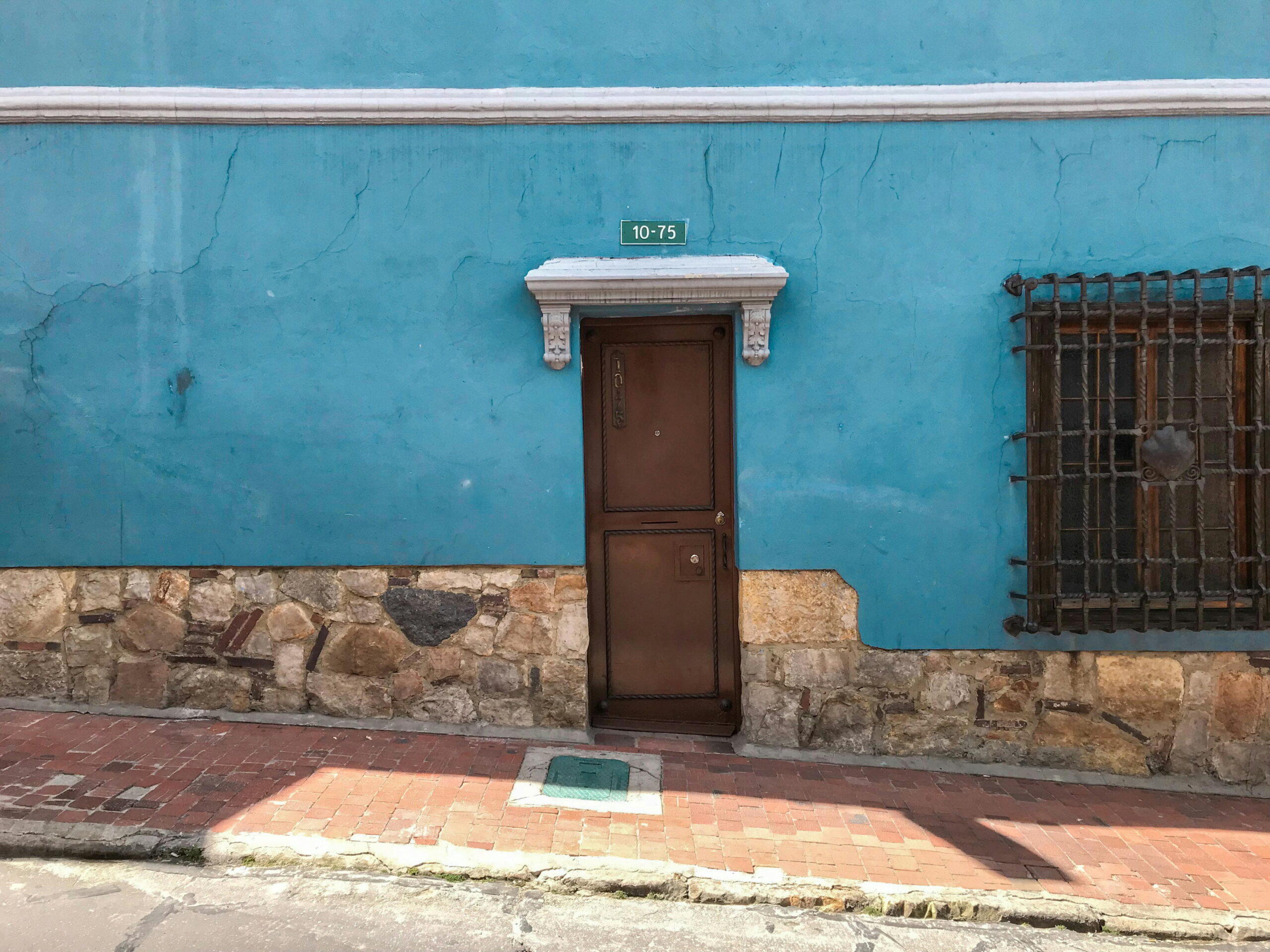 Yorkshire climate and render choice: Weathered blue rendered wall with stone base and wooden door from Imple Solution 4 U Ltd rendering services
