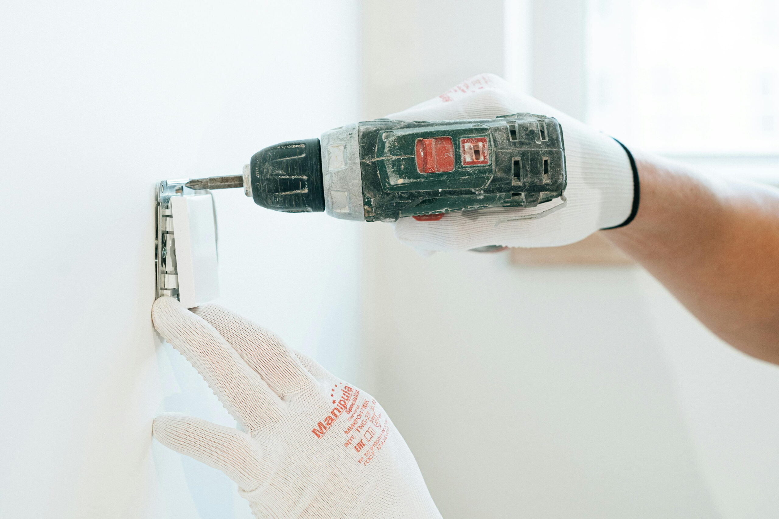Contractor performing plaster repair after settling cracks with a power drill