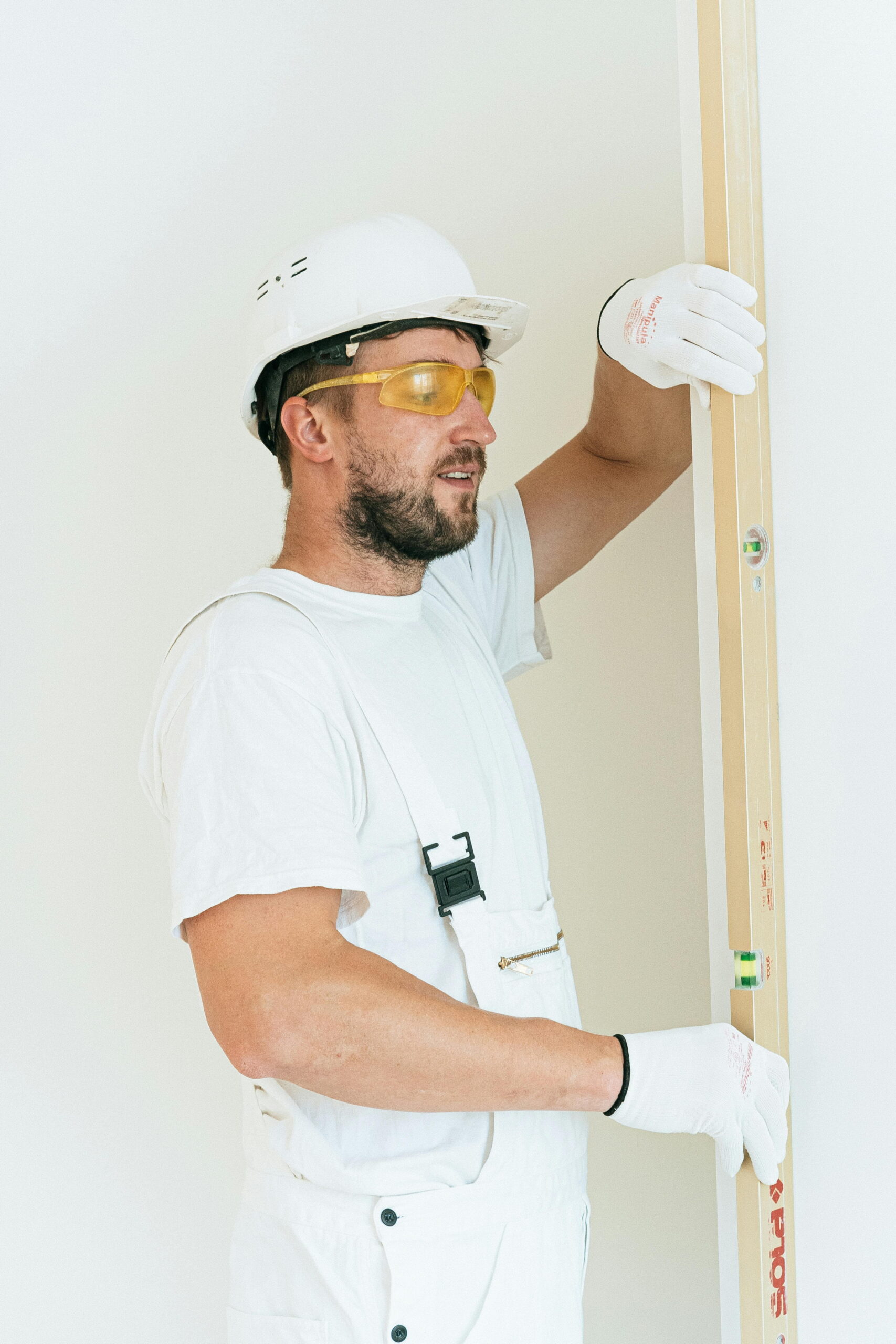 Construction worker using a spirit level on fresh render avoiding tape residue on fresh paint