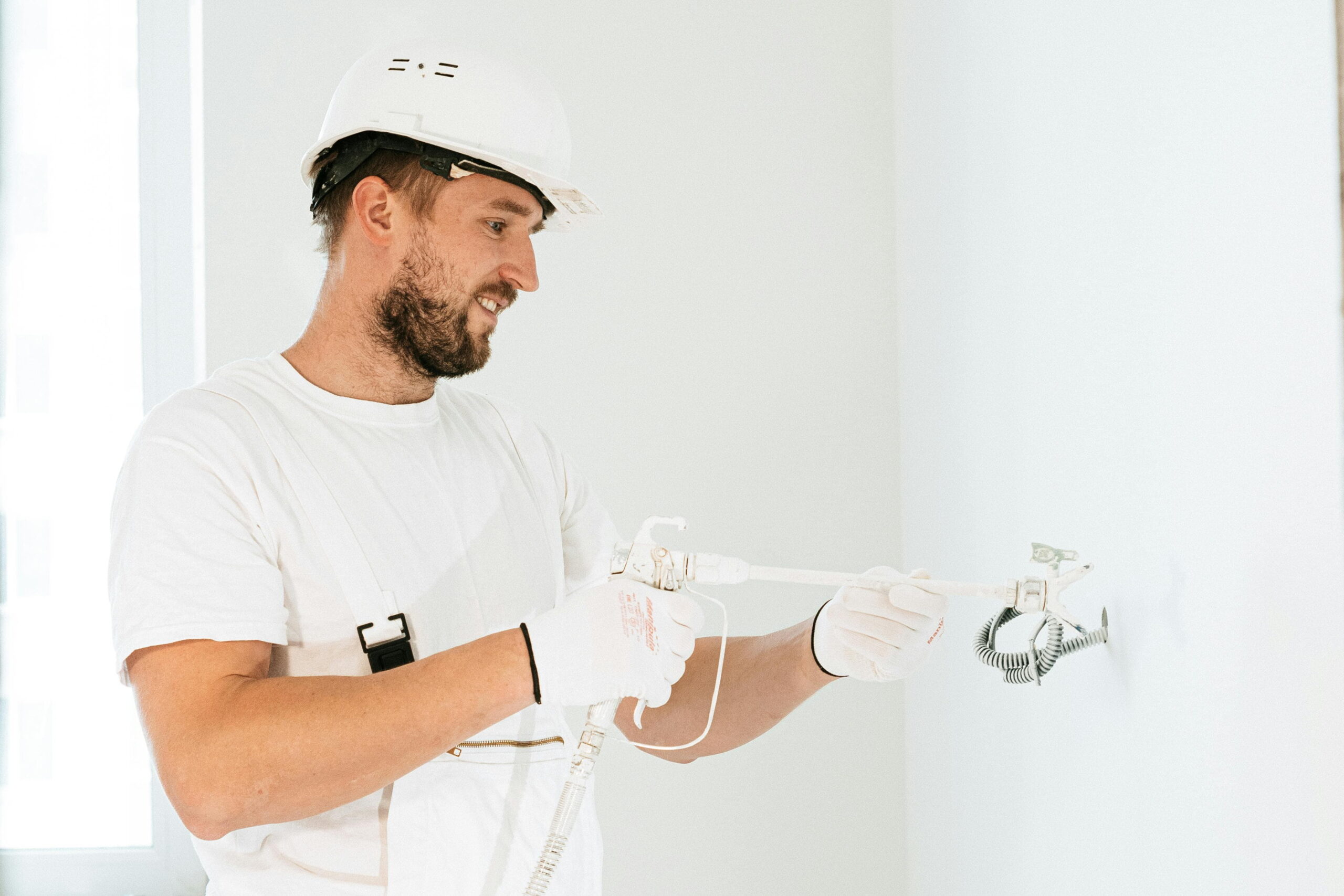 Professional applying plaster with visible airtightness tapes around frames for external rendering and plastering services
