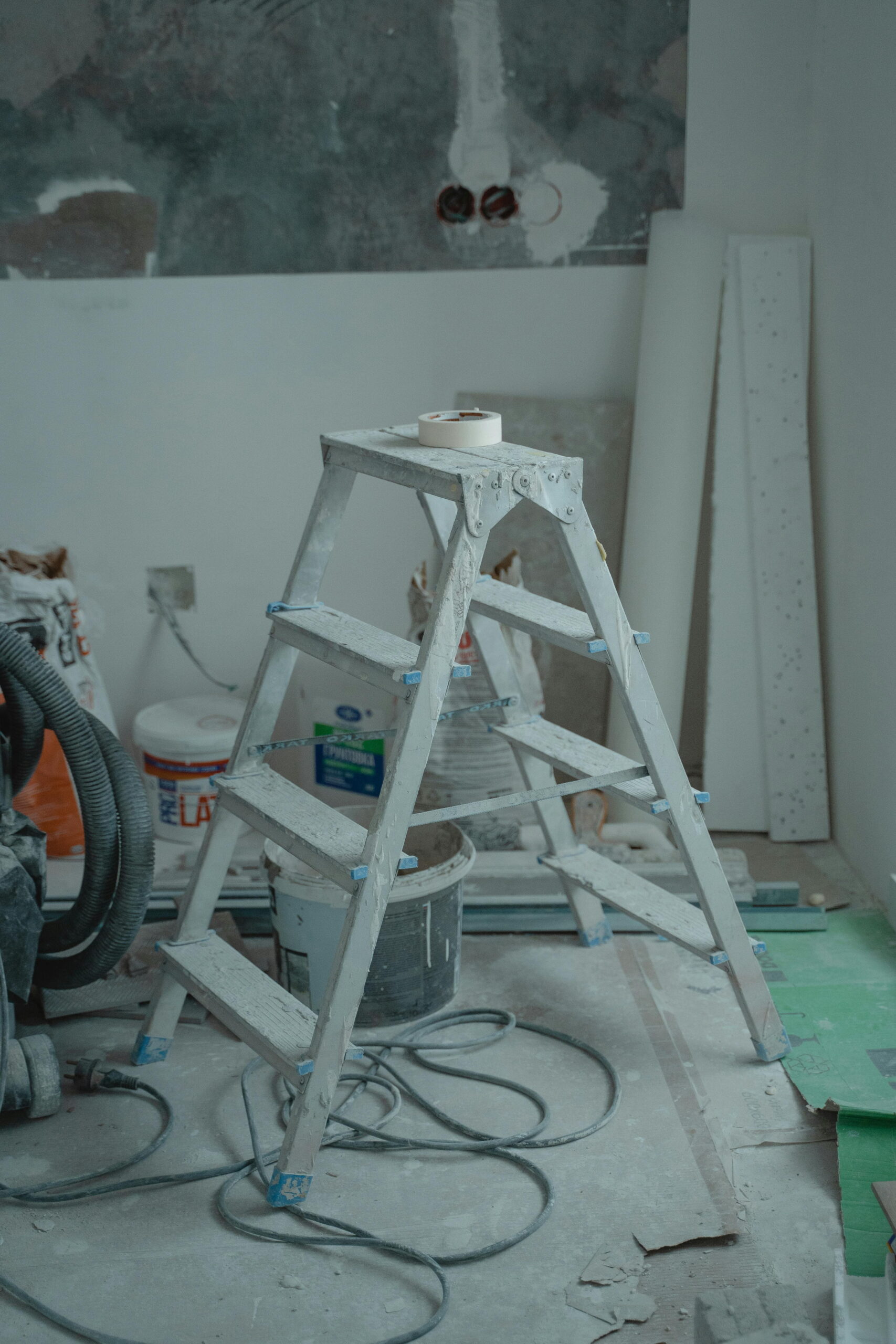 Construction scene showing integrating sill extenders with insulation around an aluminum step ladder during external rendering