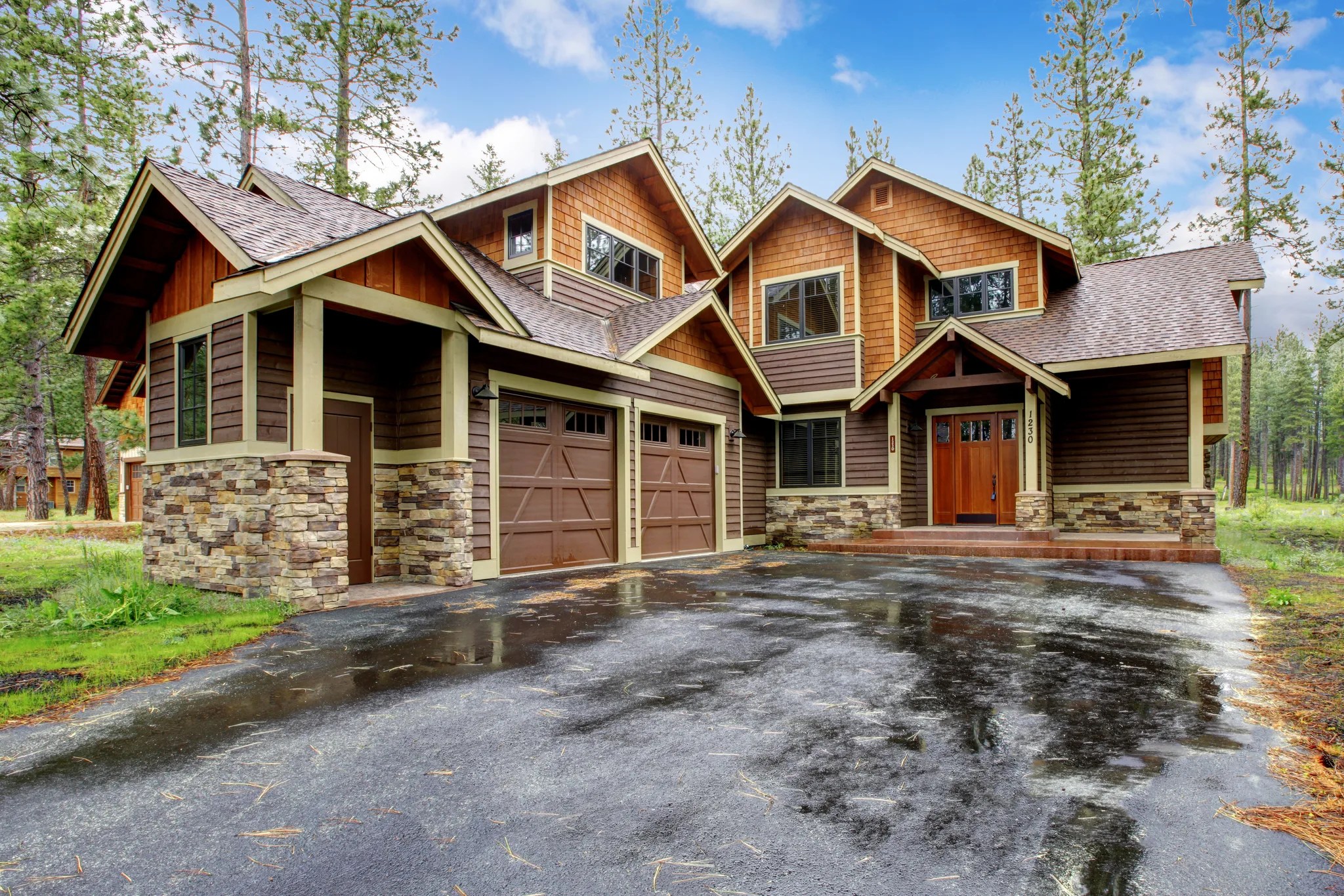 A large cedar and stone mountain home seen from its driveway