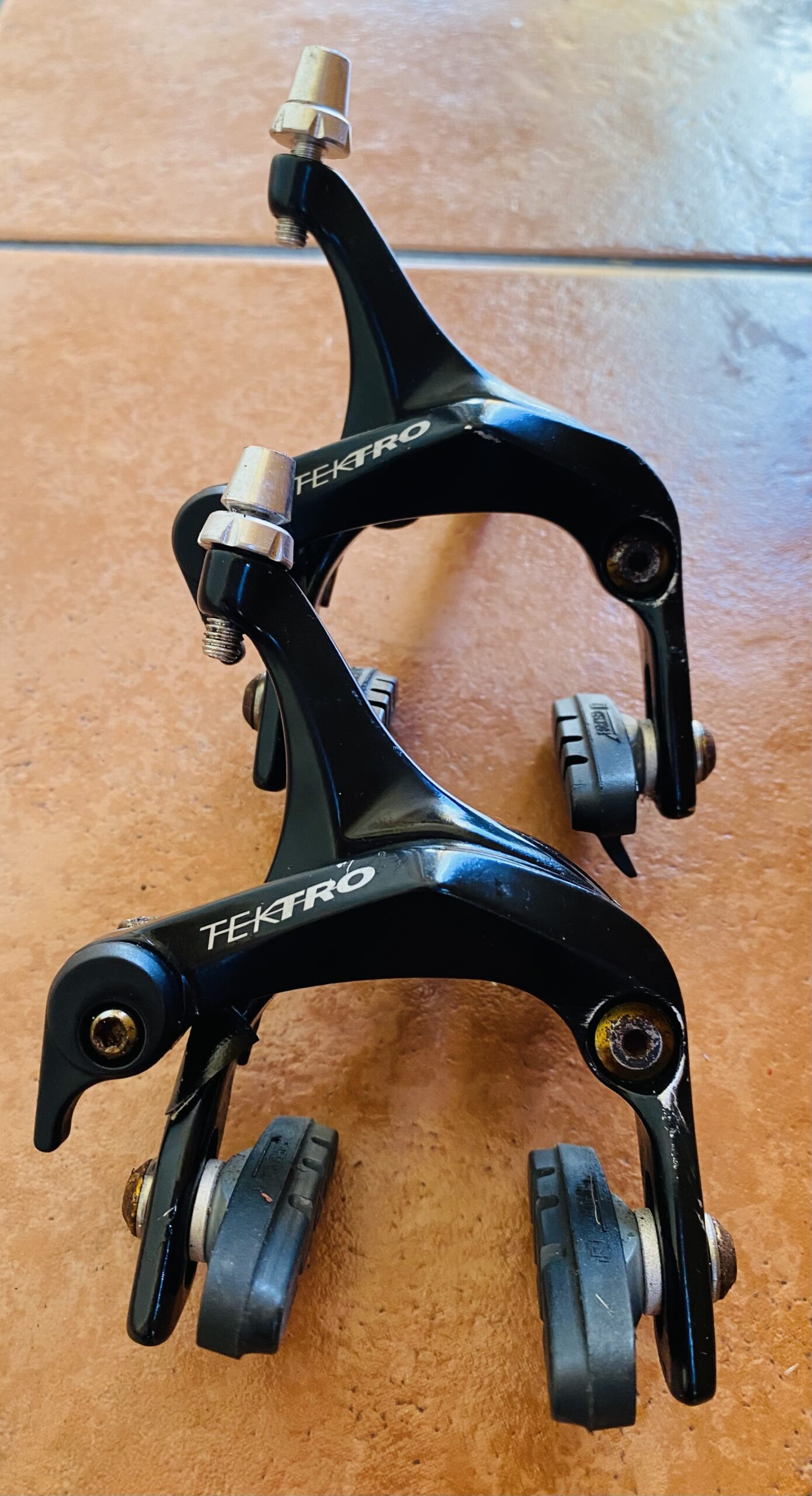 Pair of Tektro R312 dual-pivot road brake calipers in black with brake pads fitted.