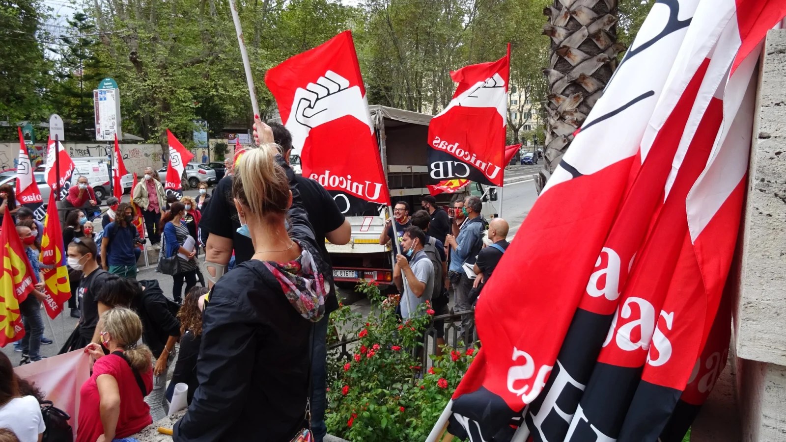 Manifestantes con banderas rojas, blancas y negras de CIB Unicobas en una concentración sindical en Italia