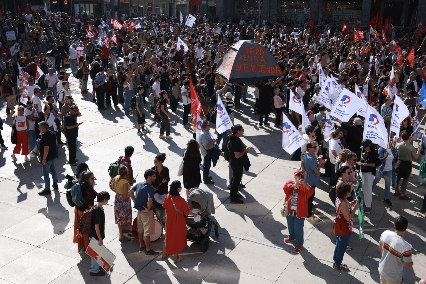 Vista panorámica de una manifestación multitudinaria en Oporto el 17 de octubre de 2026, con banderas sindicales y una pancarta sobre los alquileres.