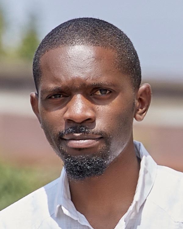 A headshot of Jacques Balolage, an African man with short hair and circle beard.