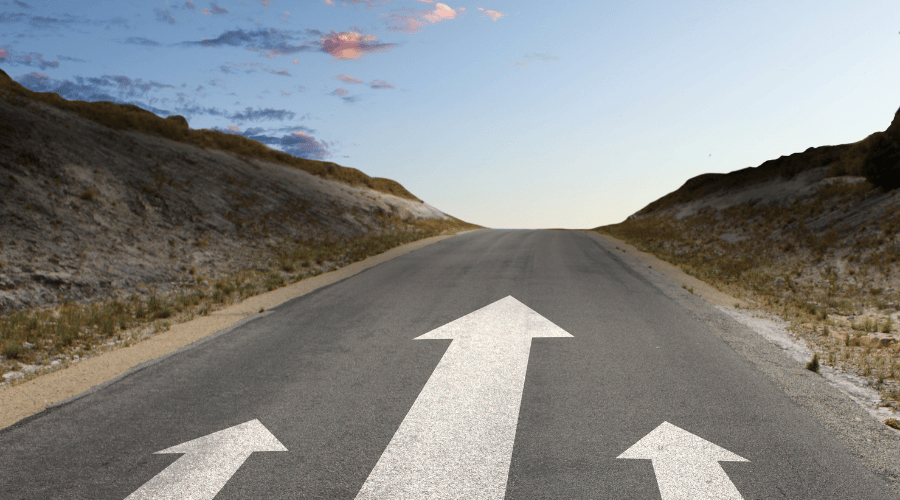 Photo of a road with arrows pointing forward toward the horizon