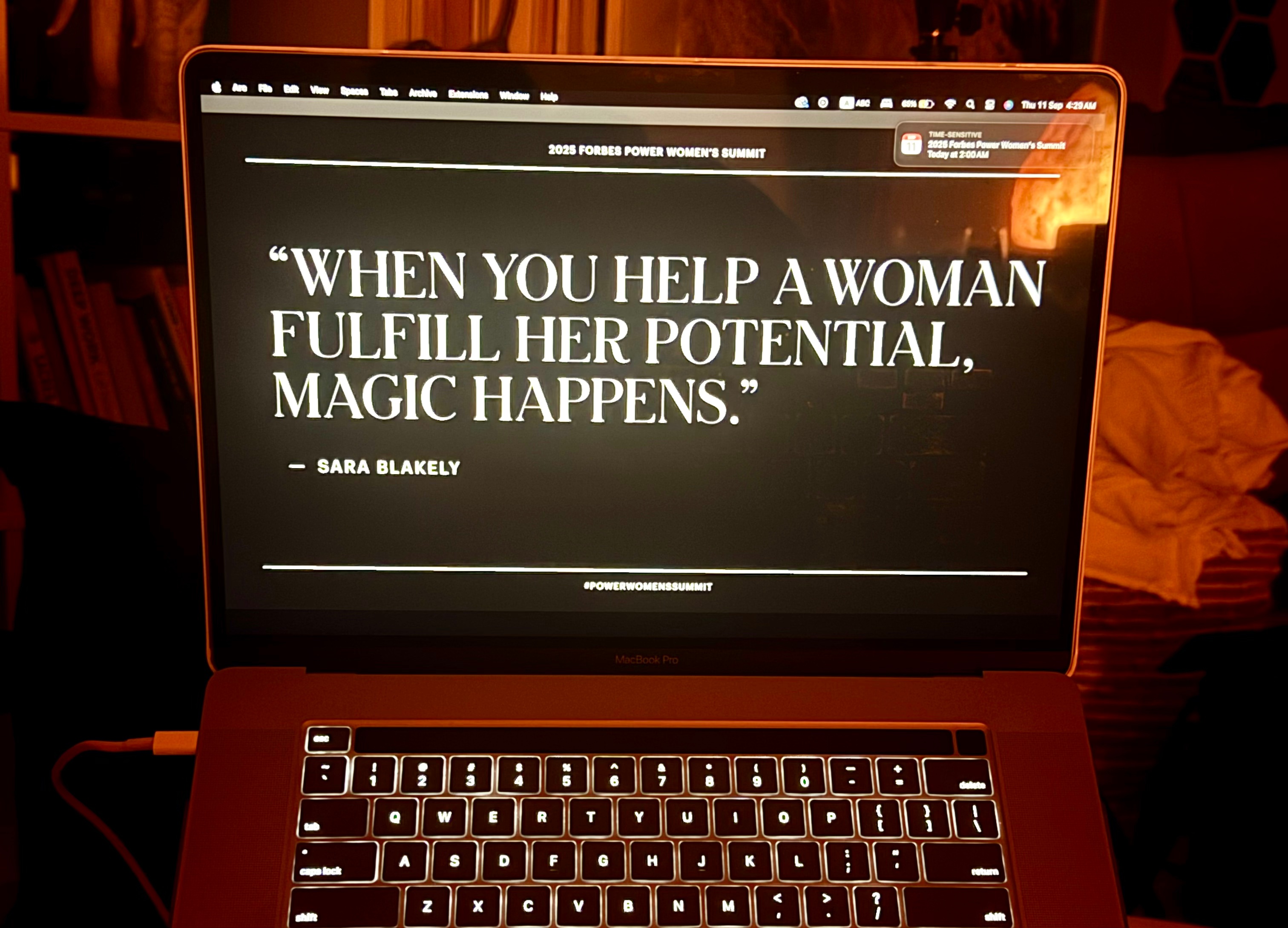 Laptop screen showing a slide from the 2025 Forbes Power Women's Summit with Sara Blakely's quote: 'When you help a woman fulfill her potential, magic happens.