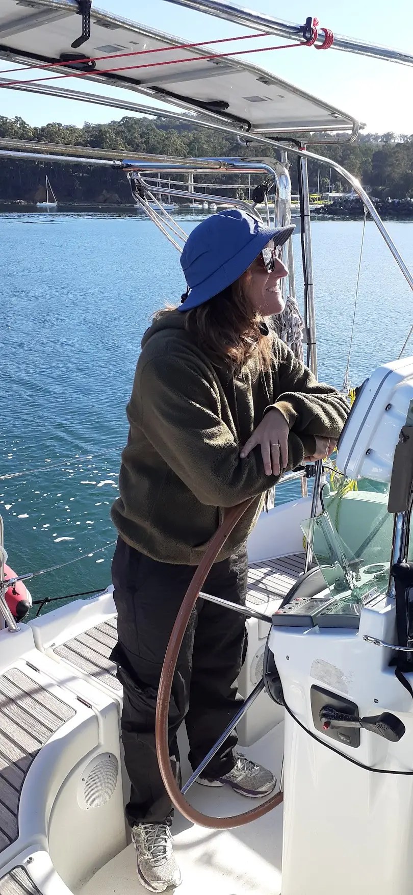 Woman at the helm of a sailboat - calm day - happy face