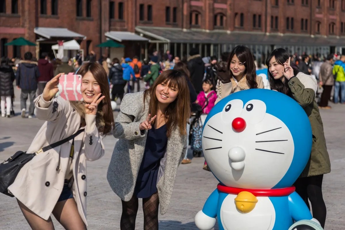Girls take photo with Doraemon figure