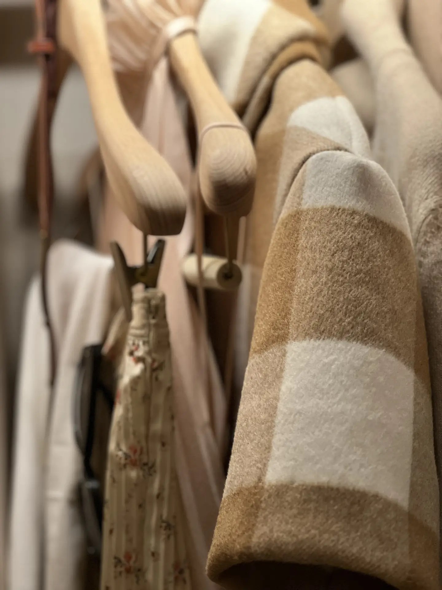 Close-up of a light tan and natural mélange sumptuous double-faced wool jacket featuring a rich tartan motif, styled with soft neutral garments in the Aman New York’s elegant spa.