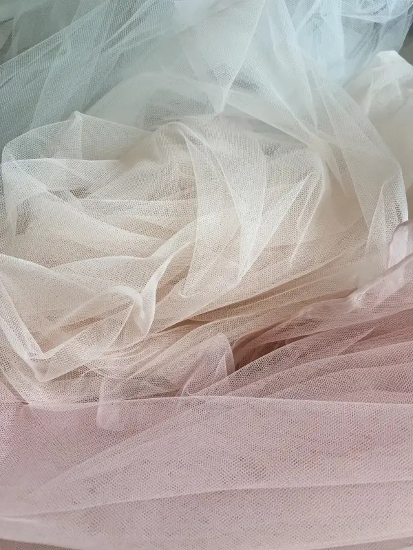 Close-up of the base layers of the SKYLAR Gown of Seasons couture gown, featuring tulle in Celestial Mist, Ivory Glow, and Blush Petal hues, with a Golden Light layer beneath, showcasing the flowing textures and luxurious palette.