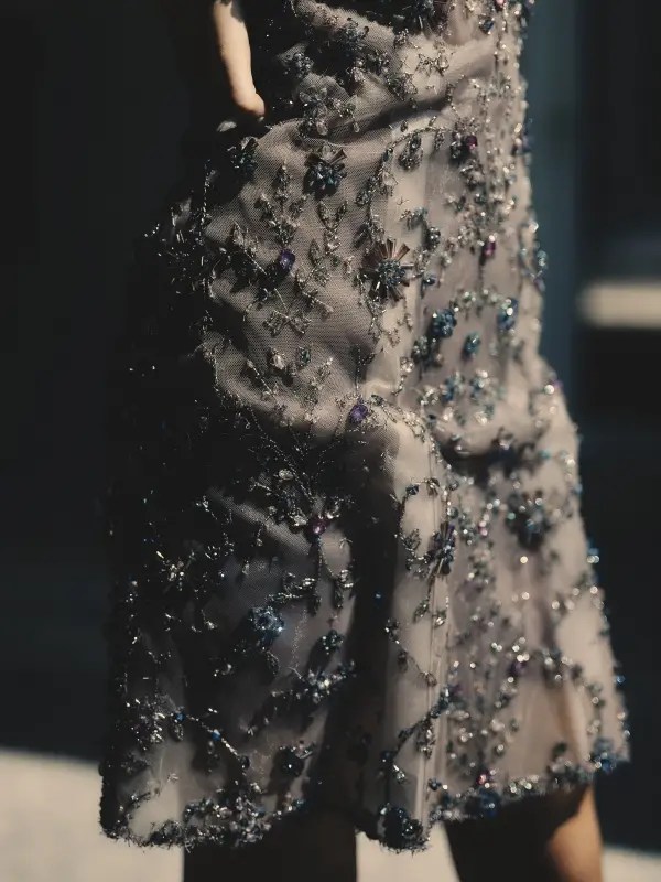 A close-up of the Shooting Star Embroidered Jewel Dress, its sheer silk organza illuminated by cascading hand-sewn star motifs and Swarovski crystals. Each bead, each glint of metallic thread, catches the shifting light—echoing the fleeting brilliance of a meteor’s passage across the night sky.