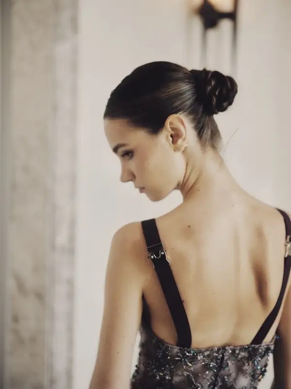 A glimmer suspended in time. The model’s back is framed by deep plum straps with polished metal fastenings, a structured contrast to the delicate Shooting Star Dress. Swarovski crystals and hand-sewn star motifs scatter across silk organza like meteors igniting upon entry—burning bright, fleeting, unforgettable.