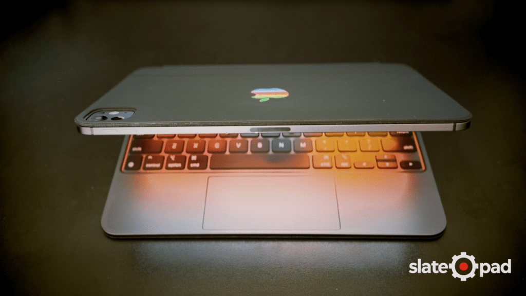Partially open iPad Pro Magic Keyboard with the light from the screen reflecting on the keyboard. 