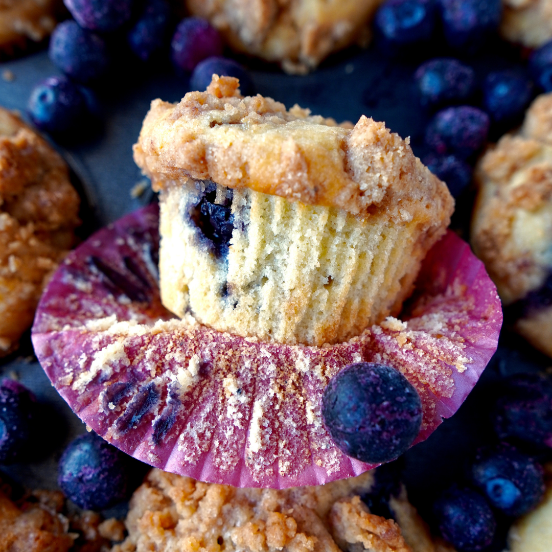 Dark gray tray of blueberry muffins with extra blueberries on the tray.