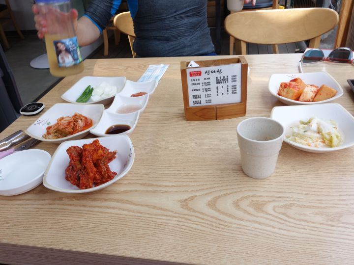김치, 양파, 소스 등 여러 밑반찬과 탁상용 메뉴판이 세팅된 나무 테이블.
