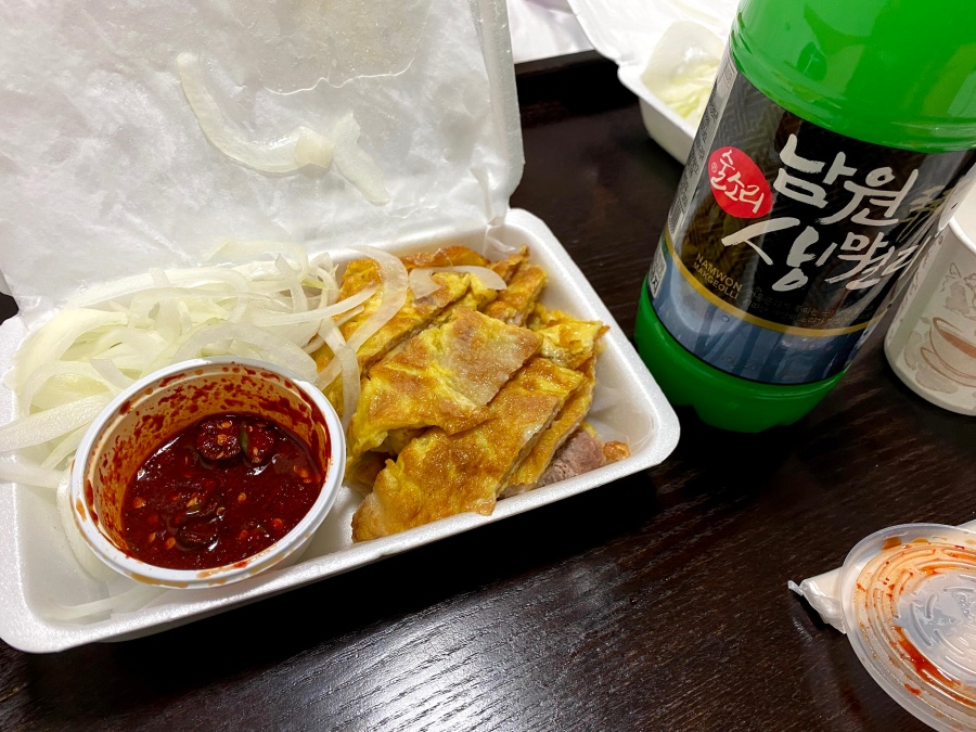 스티로폼 용기에 담긴 육전과 양파채, 붉은 양념장, 그리고 남원 생막걸리 페트병이 놓여 있다.