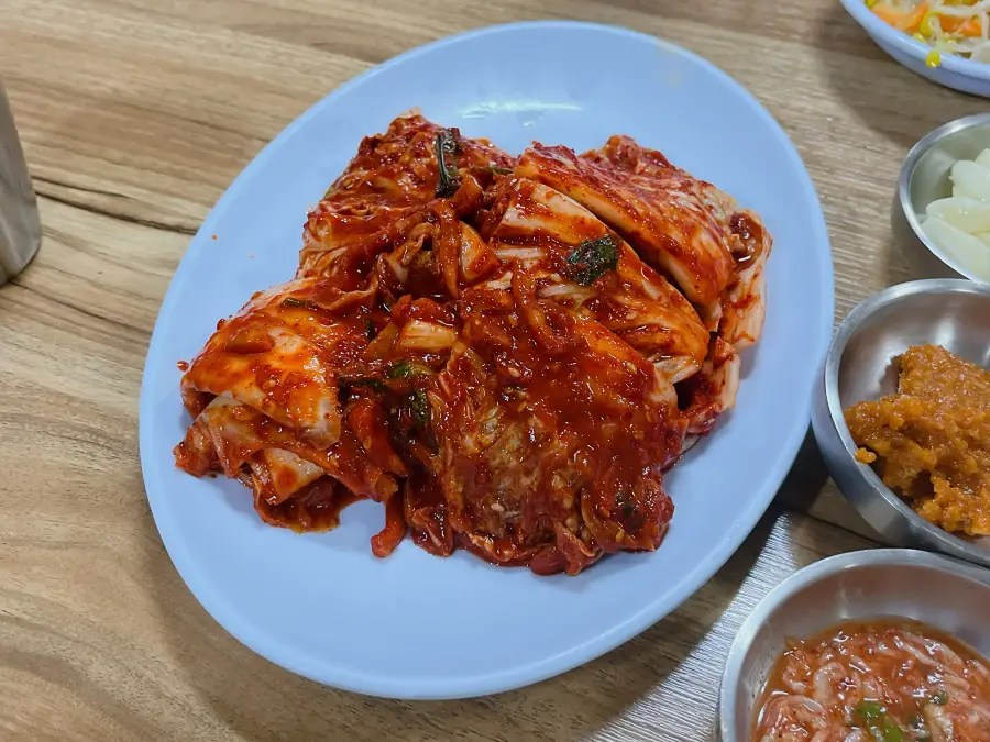 하늘색 접시에 양념이 듬뿍 발린 배추김치가 썰려 있는 모습