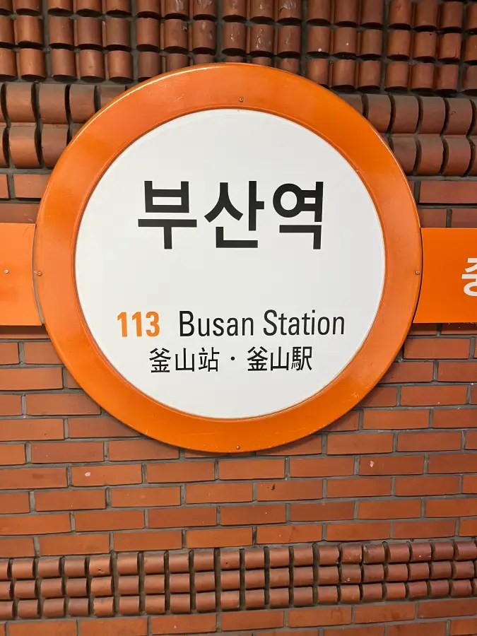 주황색 테두리가 있는 부산역 113번 지하철역 원형 간판.