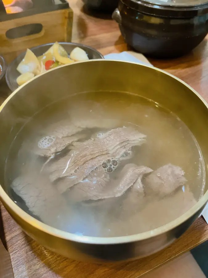 놋그릇에 담긴 맑은 국물과 얇게 썬 고기