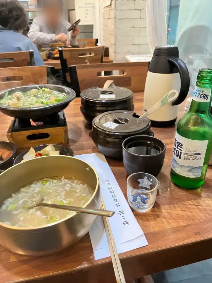 파가 들어간 곰탕과 수육, 소주병이 놓인 식당 테이블