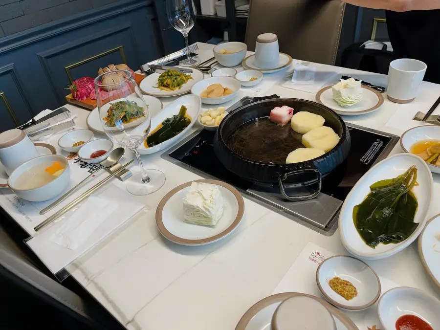 감자가 올려진 무쇠 팬과 다양한 밑반찬이 차려진 식당 테이블 상차림