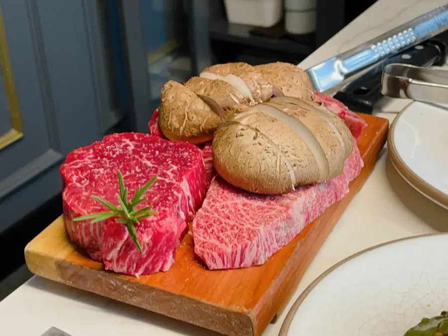 나무 도마 위에 로즈마리와 함께 올려진 두툼한 생소고기와 얇게 썬 표고버섯