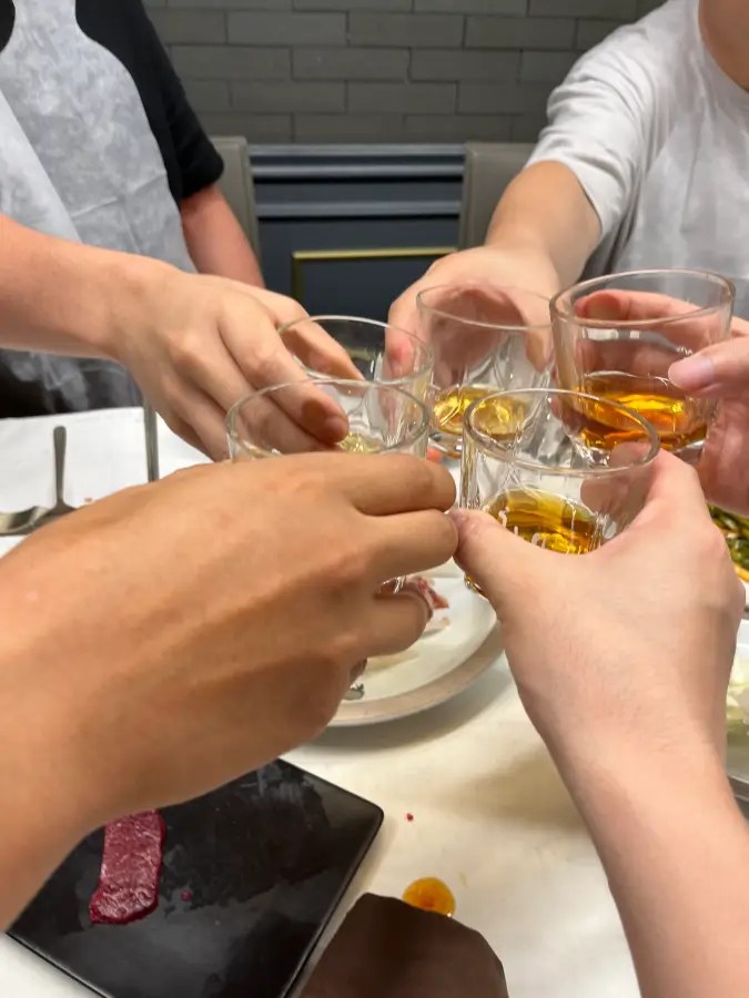 식탁에 둘러앉은 사람들이 각자의 유리잔을 부딪치며 건배하는 모습
