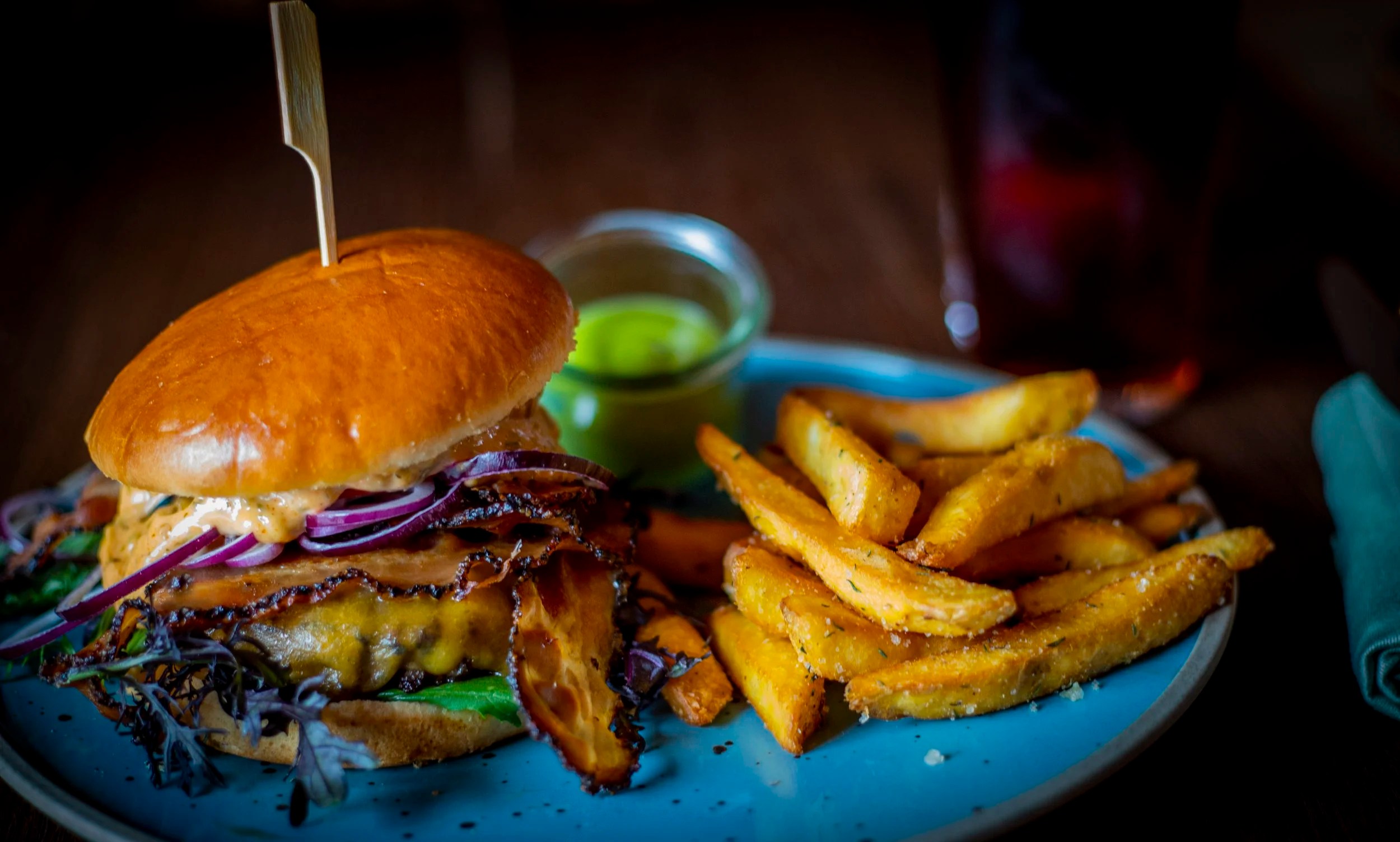 Burger med ost og løg samt pommes frites på Restaurant Den Gamle Stalds eget foto.