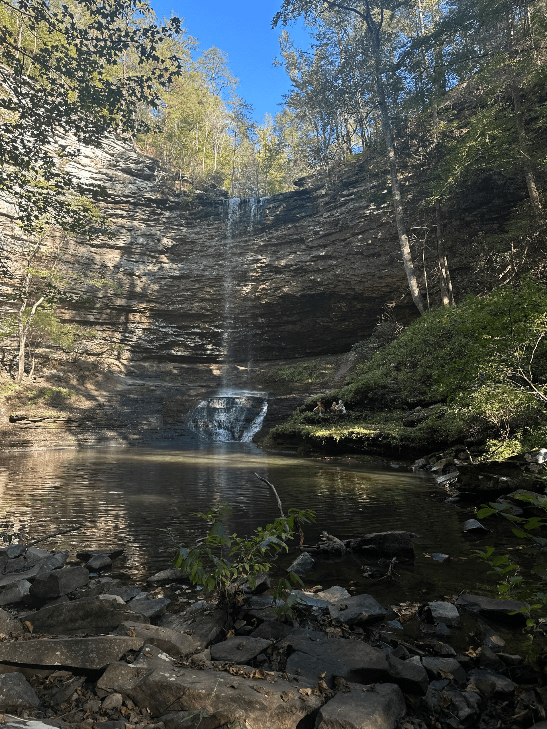 A family of five hiking together on a sunny fall afternoon, standing near a waterfall surrounded by colorful autumn trees — symbolizing faith, gratitude, and embracing fullness in everyday life.