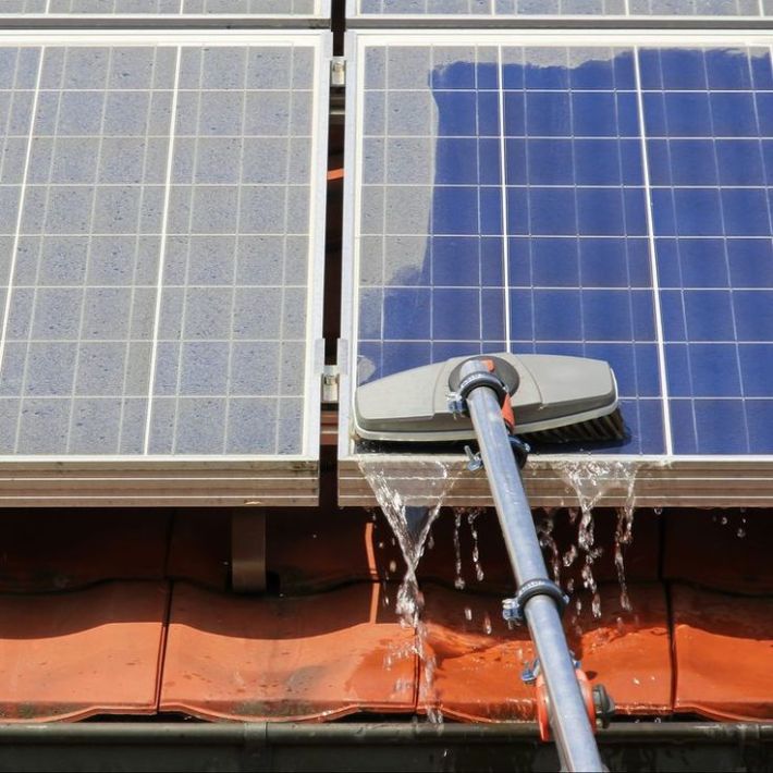 A close-up of solar panels being cleaned with water flowing off them.