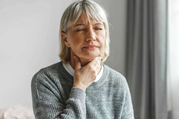 Woman feeling her throat muscles as she begins huff coughing after airway clearance therapy.