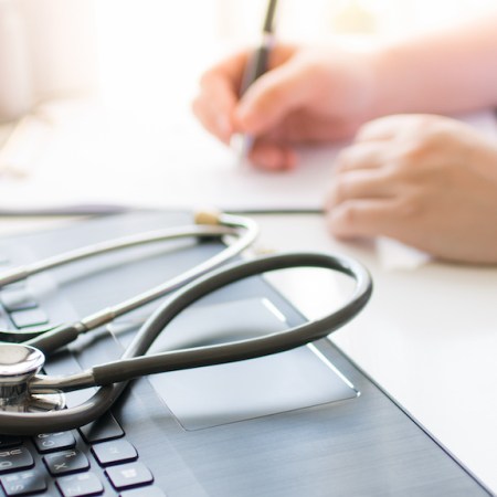 Female clinician writing prescription as part of patient's bronchiectasis treatment.