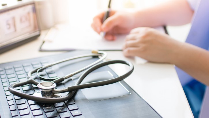 Female clinician writing prescription as part of patient's bronchiectasis treatment.