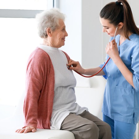 Older woman with COPD getting lungs checked in clinician office.