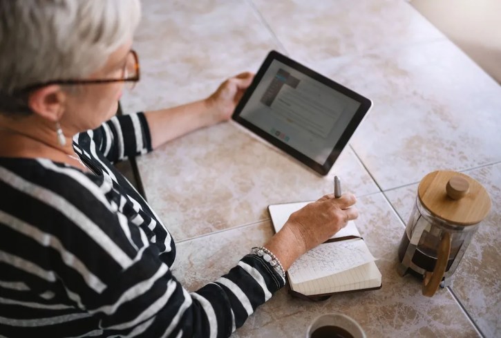Woman looking at screen of tablet in home.