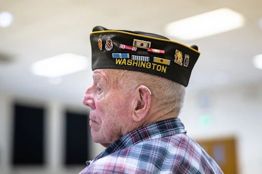 Veteran wearing decorated military hat.