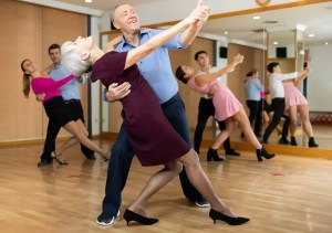 Adult students practicing ballroom dancing together in a group lesson