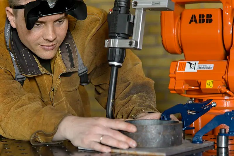 Selecting the Right Robotic Welding System for Your Business 4 An example of an industrial robotic welding system with an operator lining up the weld piece