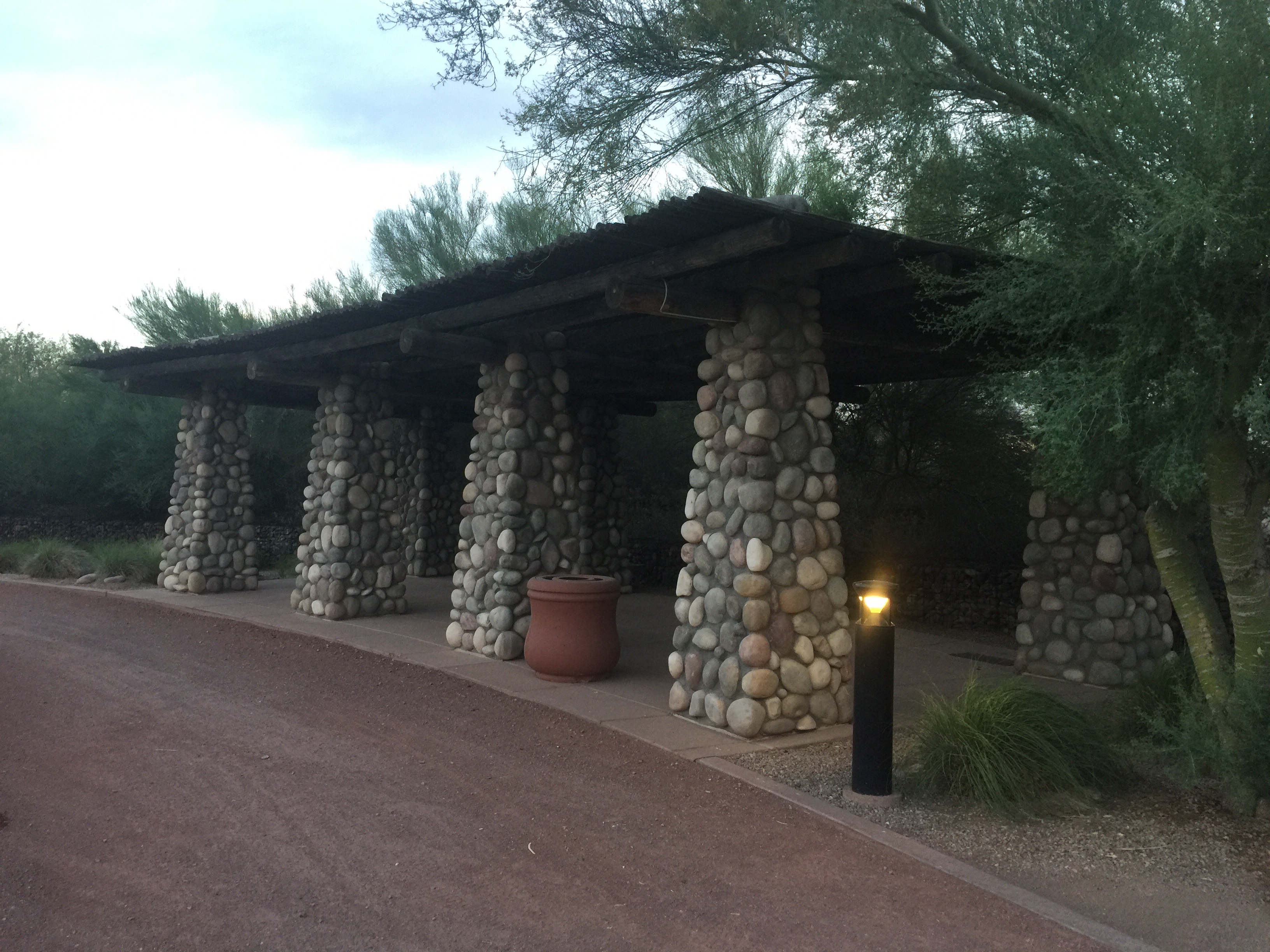 Southwestern style pergola with river rock columns with Palo Verde trees all around.