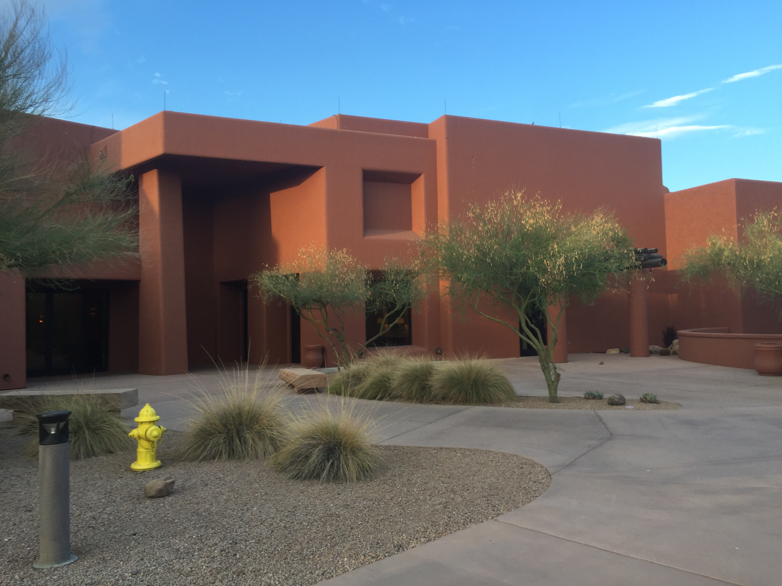 Orange southwest styled conference building with desert landscaping in front.